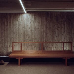 Minimal wooden bench against a textured wall