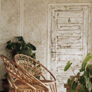 Woven chairs and wooden bench in a leafy courtyard